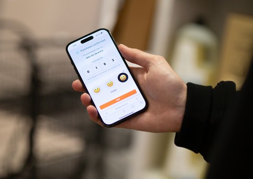 A hand holding a phone showing a Scan & Go purchase-confirmed checkout screen