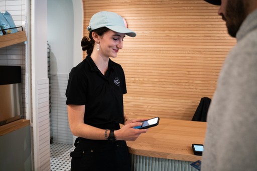 A store team member reviewing a phone at the counter while a colleague waits nearby.